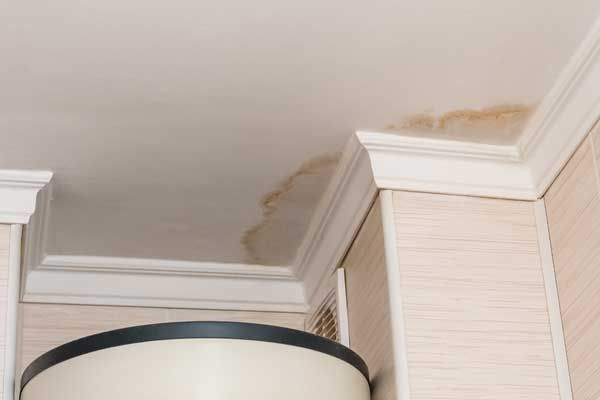 A ceiling with water stains on it and a lamp.