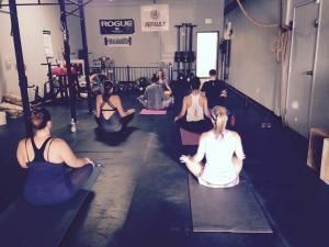A group of people are sitting on yoga mats in a gym.