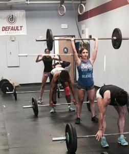 A group of people are lifting barbells in a gym.