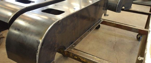 Welded metal components on a wheeled cart in a workshop setting.