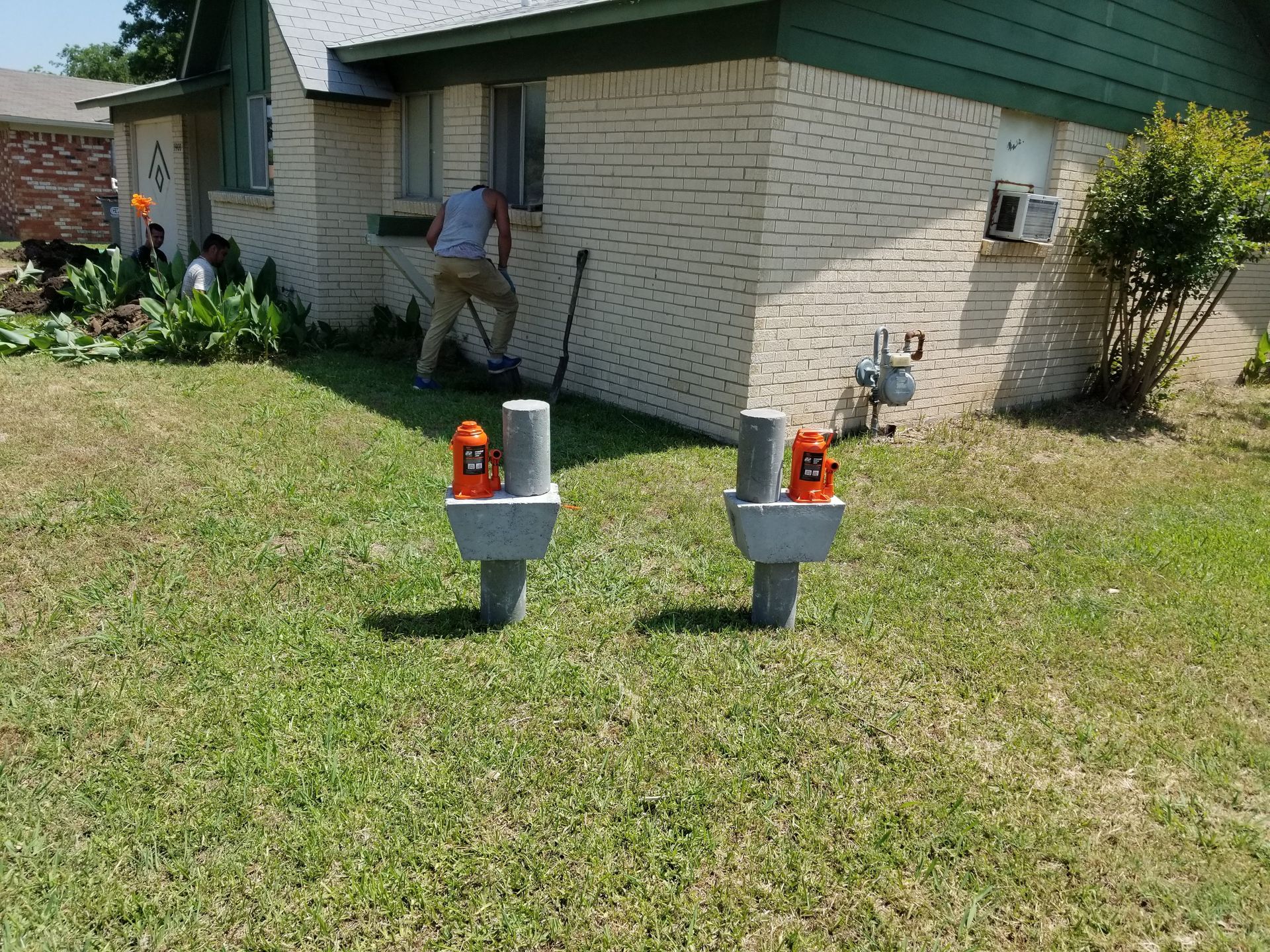 A man is digging in the grass in front of a house