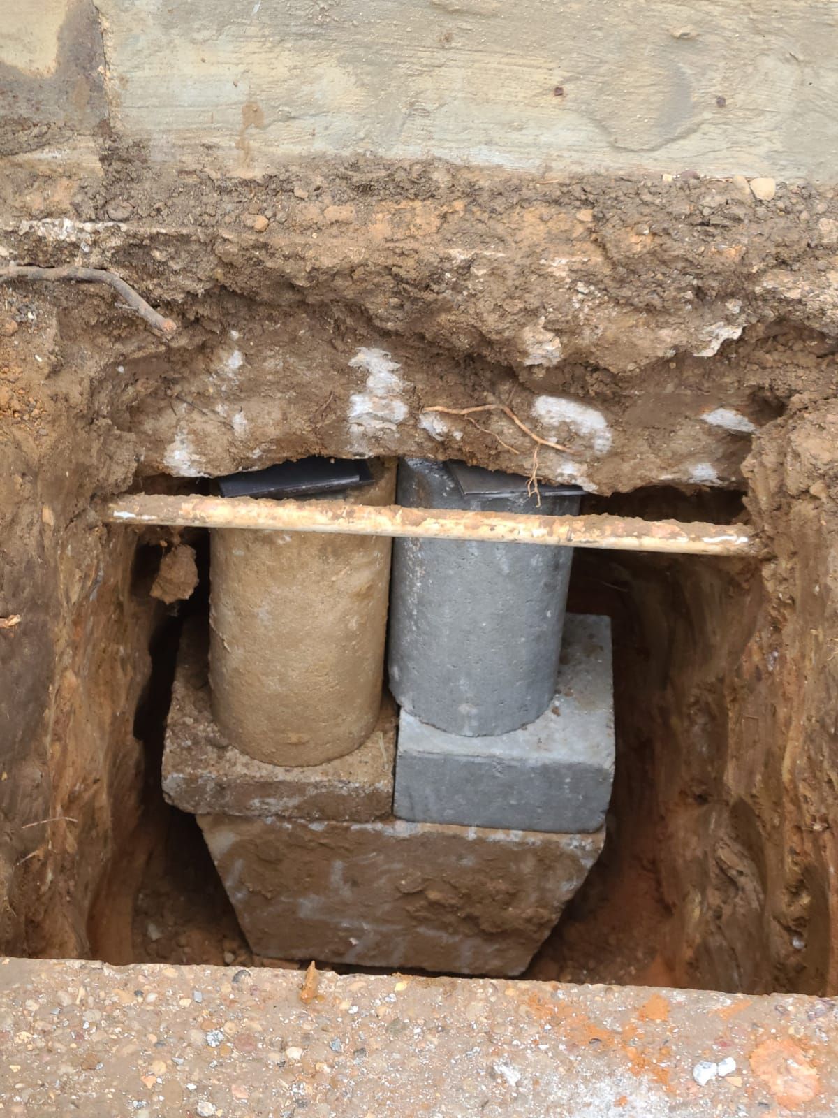 Two concrete cylinders are sitting in a hole in the ground.