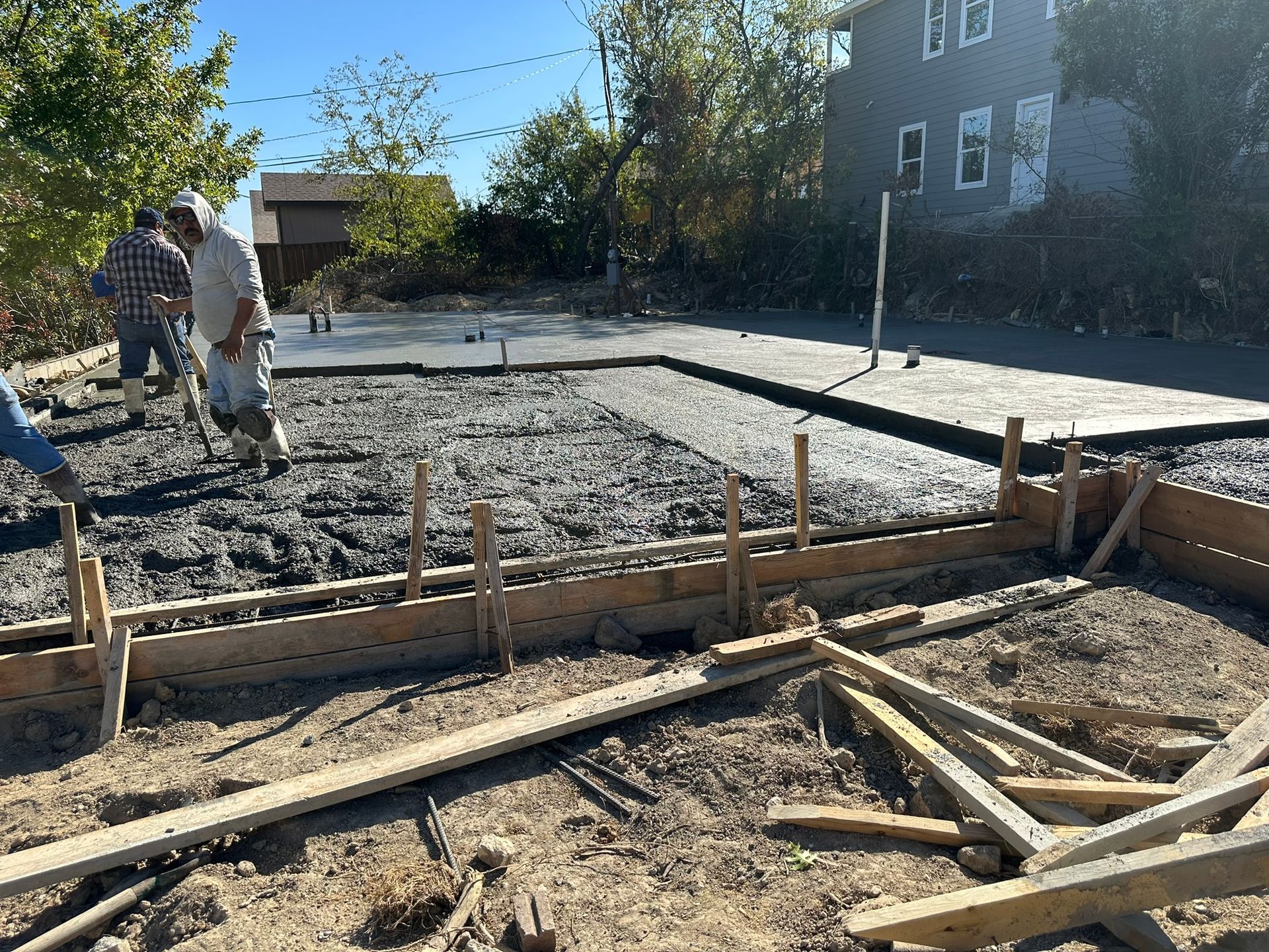 A group of men are working on a concrete base for a house.