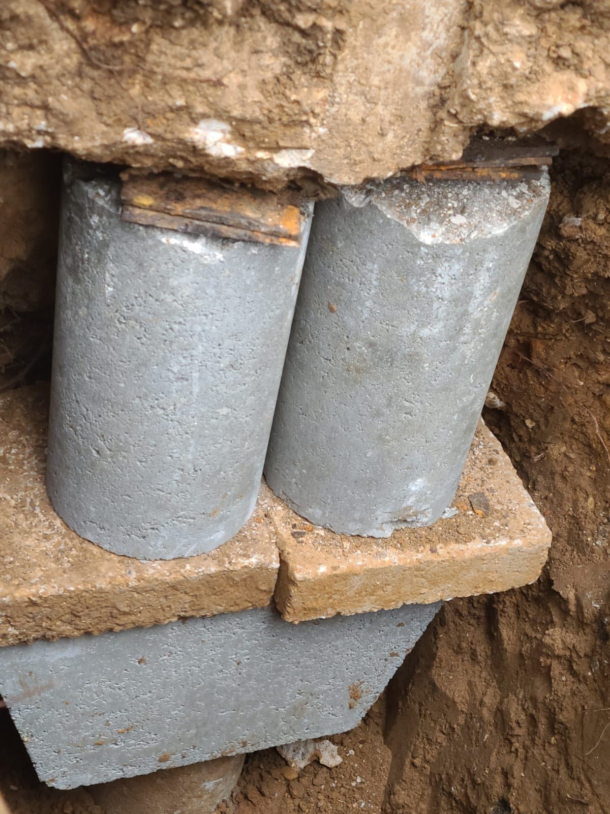 A couple of concrete blocks sitting on top of each other in the dirt.