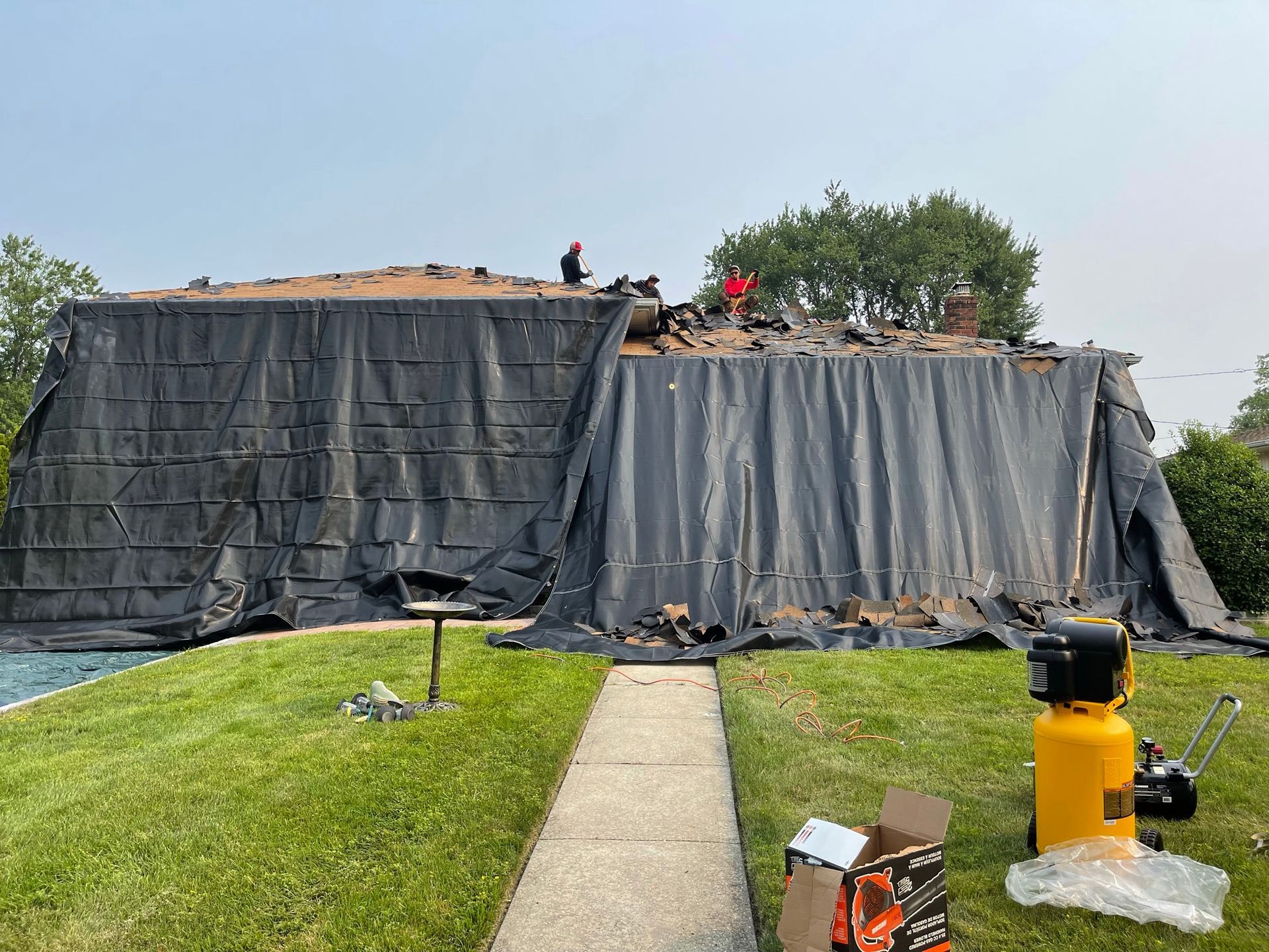 The roof of a house is being covered with a tarp.