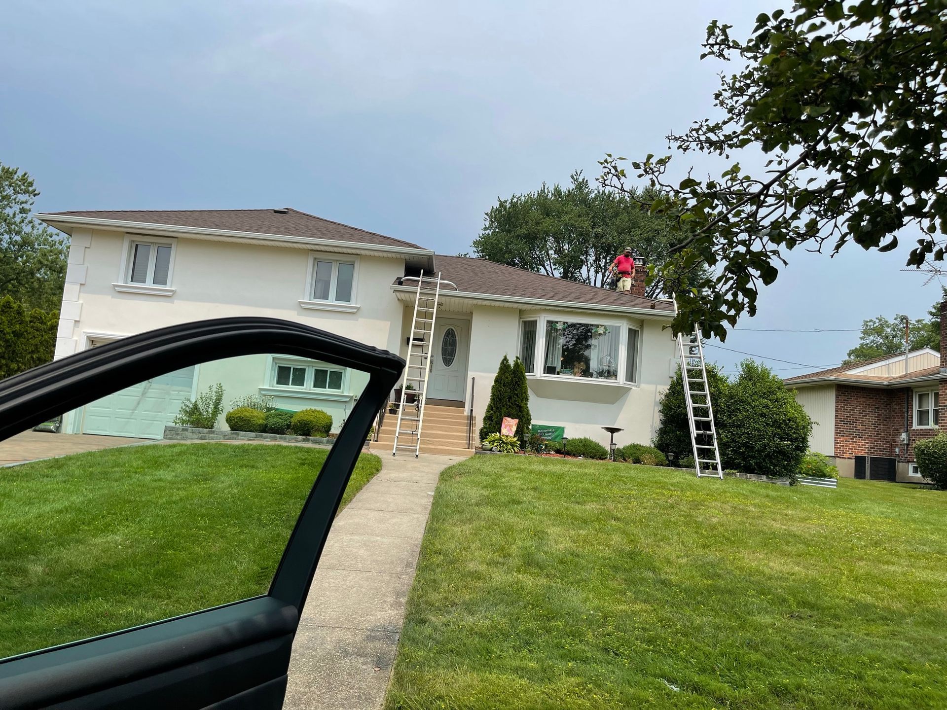 A car is parked in front of a house that is being painted.