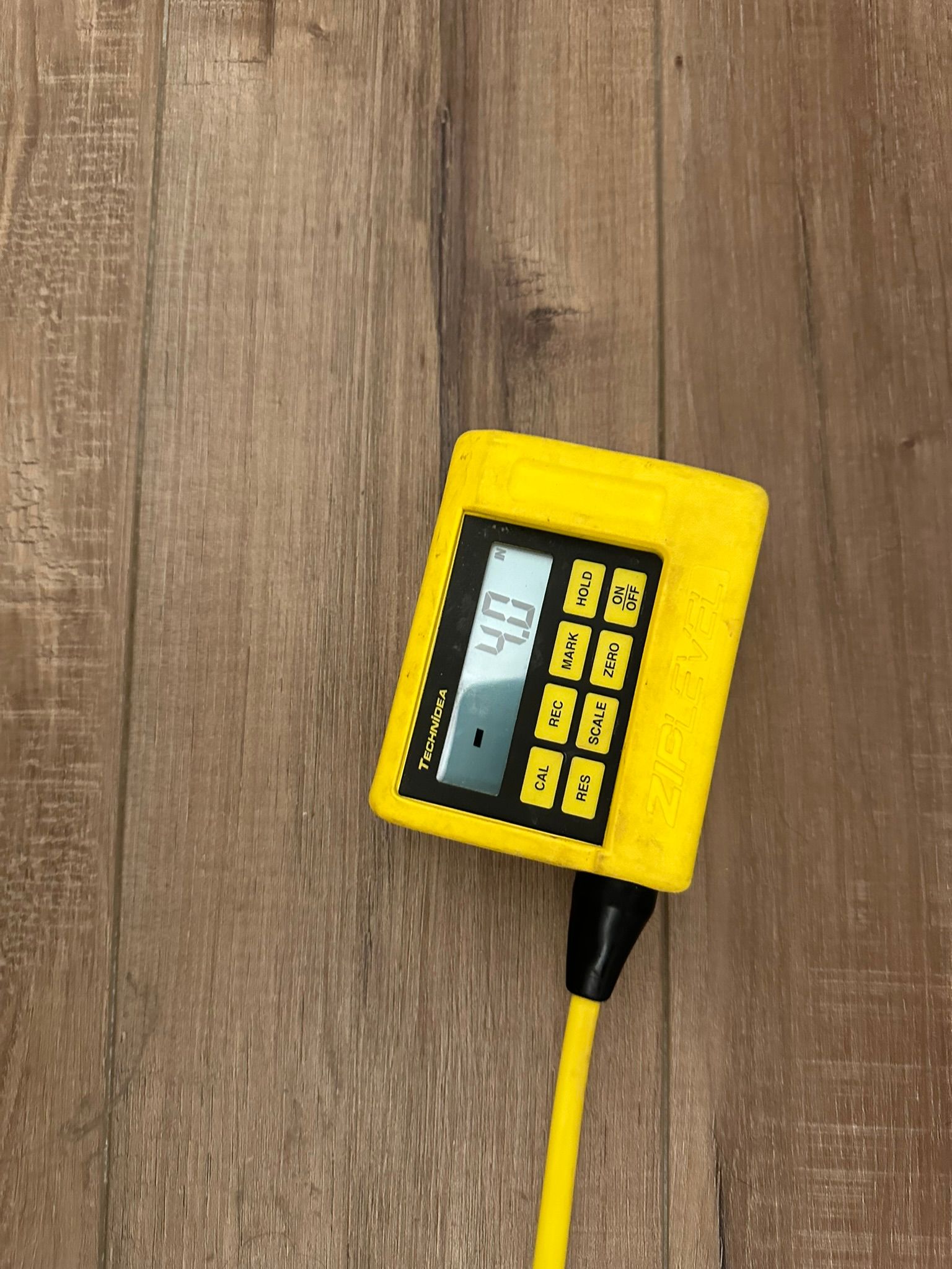 A yellow calculator is sitting on a wooden table.