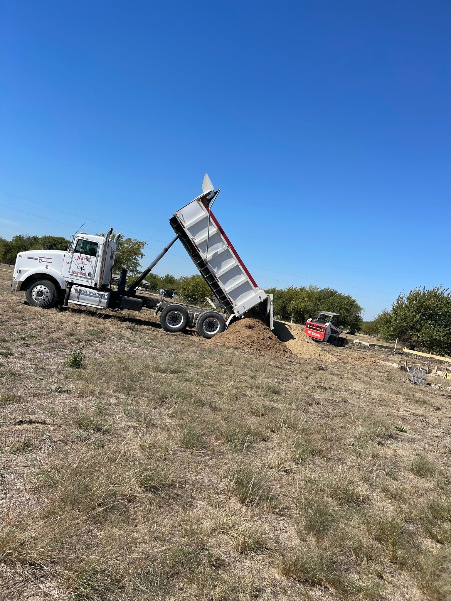 Dump Truck is Dumping Dirt Into a Field
