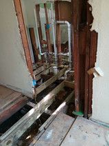 A room with a hole in the wall and pipes coming out of it.