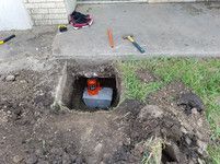 A manhole cover is being installed in a hole in the ground.