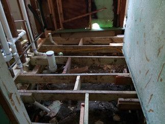 A bathroom under construction with wooden beams and pipes.