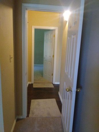 A hallway with a door open leading to a bathroom.