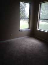 An empty room with two windows and a carpeted floor.
