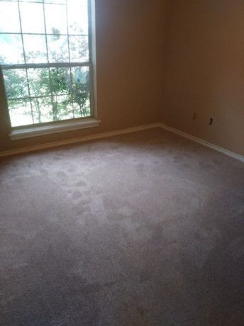 An empty room with a window and a carpeted floor
