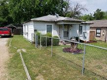 A small white house with a red truck parked in front of it.