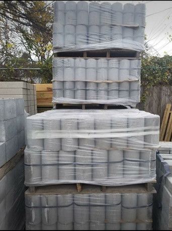 A pile of concrete blocks wrapped in plastic is stacked on top of each other.