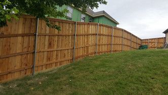 A wooden fence is in the backyard of a house.