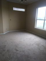 An empty room with a carpeted floor and a window.