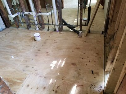 A bathroom under construction with a wooden floor and pipes.