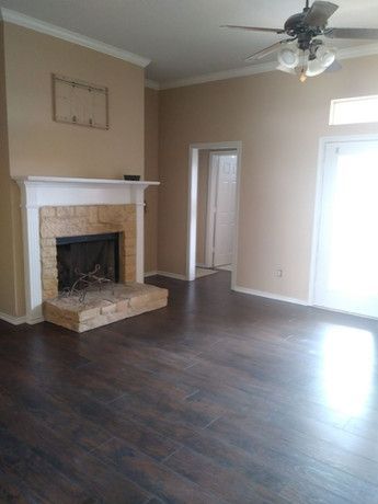 A living room with a fireplace and a ceiling fan.