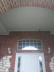 The front door of a brick house with a white door and a window.