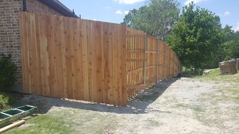 A wooden fence is being built in the backyard of a house.