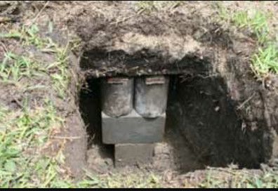 A pair of boots are sitting in a hole in the ground.