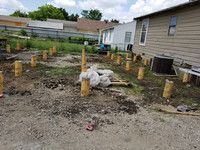 A house is being built in the backyard of a mobile home.