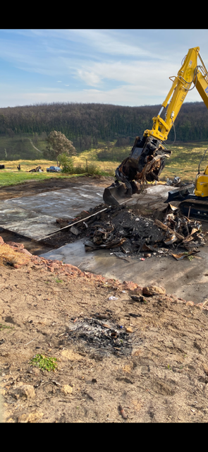 A large yellow excavator is working on a construction site.
