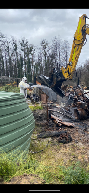 A man is standing next to a yellow excavator in a field.
