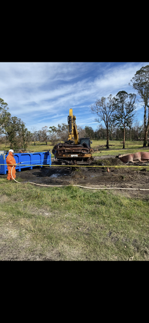 A man is standing next to a large excavator in a field.