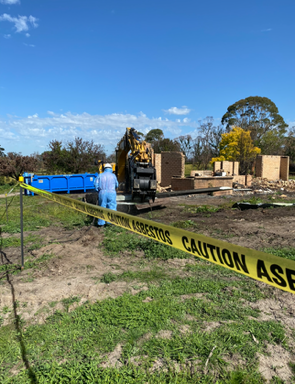A man is standing in a field next to a caution tape.