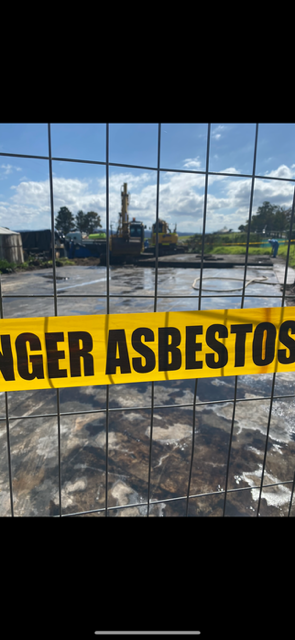 A fence with a yellow tape that says danger asbestos on it.