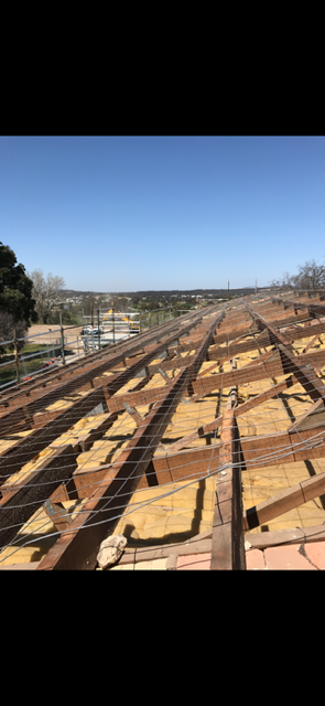 A roof with a lot of wooden beams and a blue sky in the background.