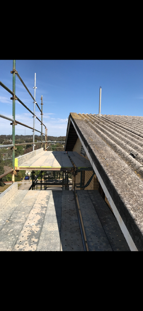 A roof with scaffolding on it and a blue sky in the background.