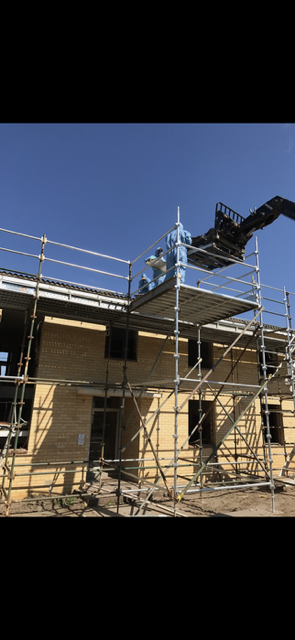 A large building is being built with scaffolding and a crane.