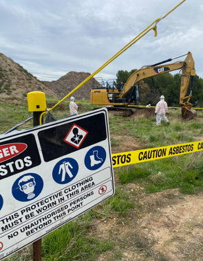 A construction site with a sign that says caution asbestos