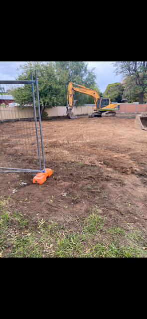 A yellow excavator is moving dirt in a dirt field.