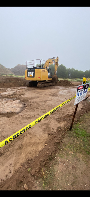 A yellow excavator is driving through a dirt field.