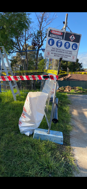 A ladder is sitting in the grass next to a sign.