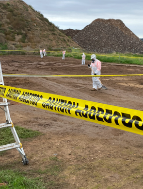 A man in a protective suit is walking behind a yellow caution tape