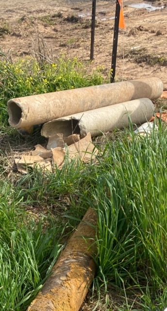 A bunch of pipes are laying on the ground in the grass.