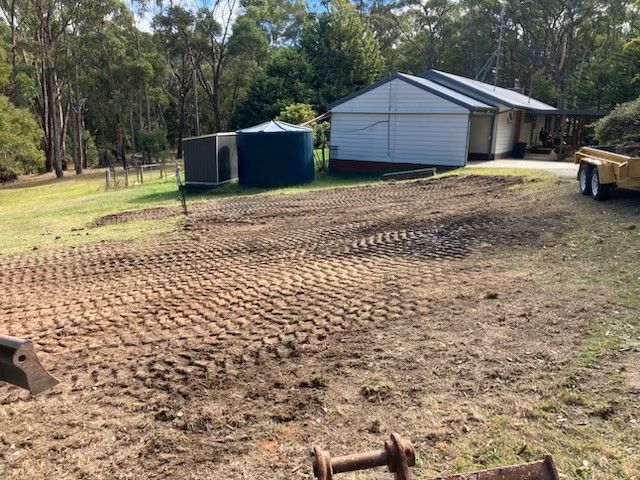A large dirt field with a house in the background.