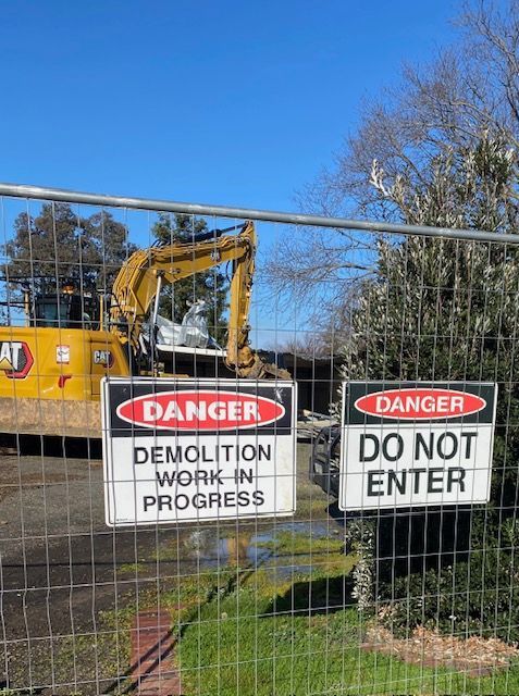 A brick house is being demolished by a bulldozer