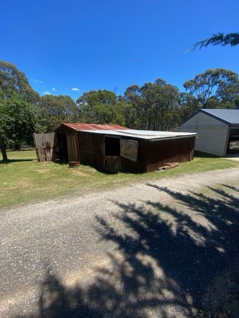 A shed is sitting in the middle of a grassy field.