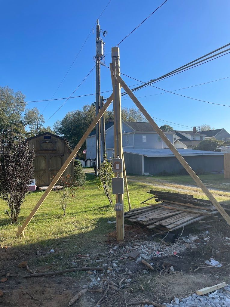 A wooden pole is sitting in the middle of a yard next to a house.