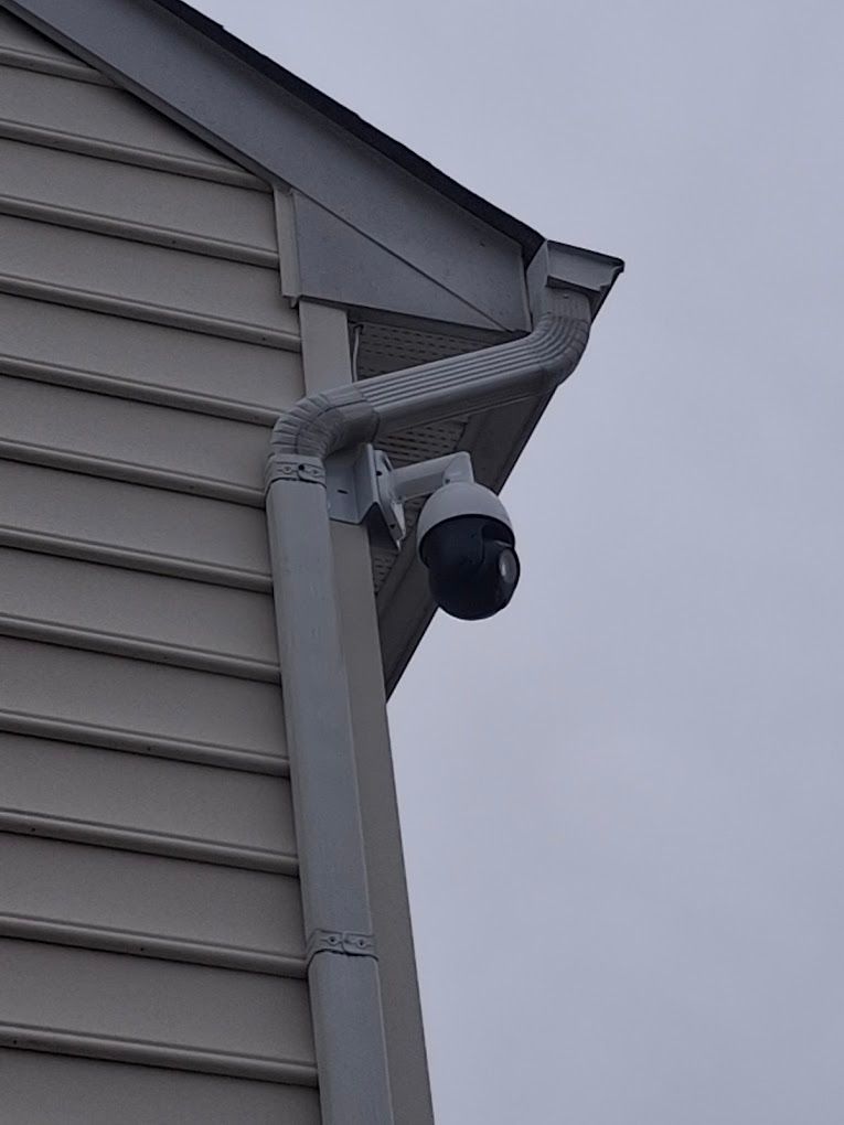A security camera is mounted on the side of a house.