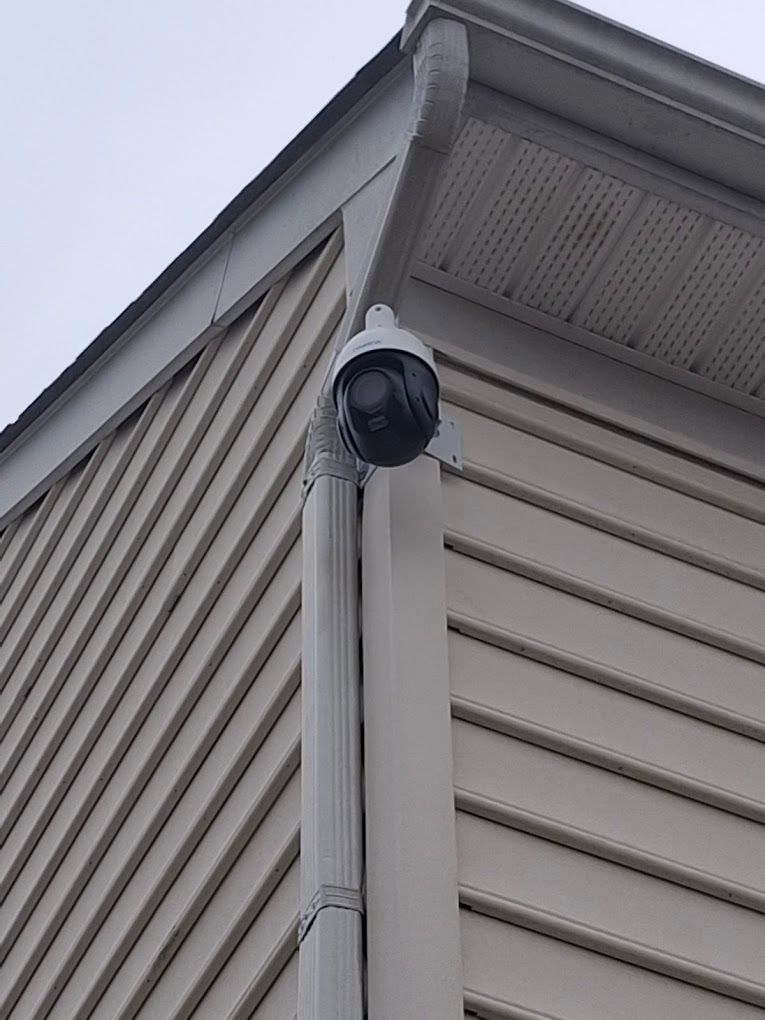 A security camera is mounted on the side of a house.