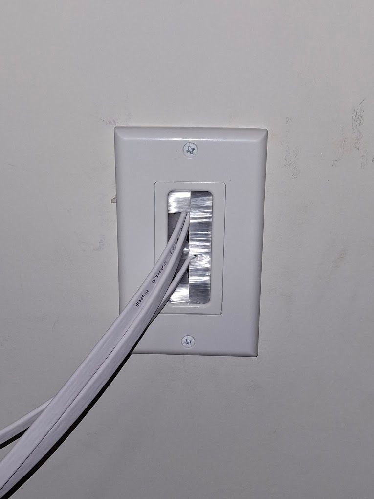 A white light switch with a cable plugged into it.