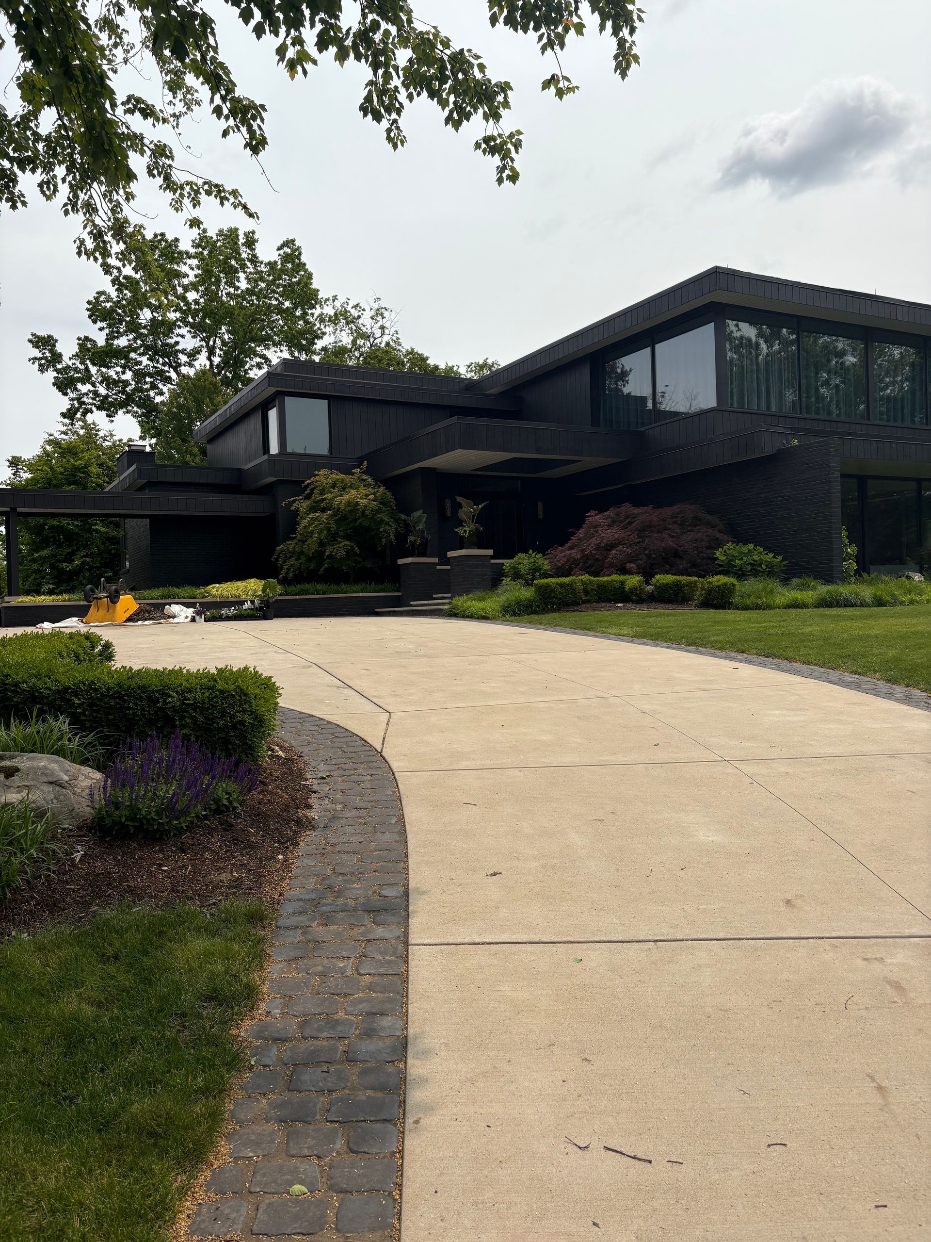A large black house with a driveway leading to it.